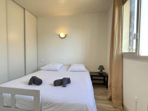 - une chambre dotée d'un lit blanc avec deux chapeaux dans l'établissement Valras-Loc - Appartement avec terrasse et parking,, à Valras-Plage