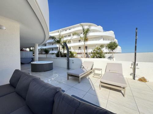 a couch and chairs on a patio with a building at Valras-Loc Archipel Panarea Spa confort in Valras-Plage