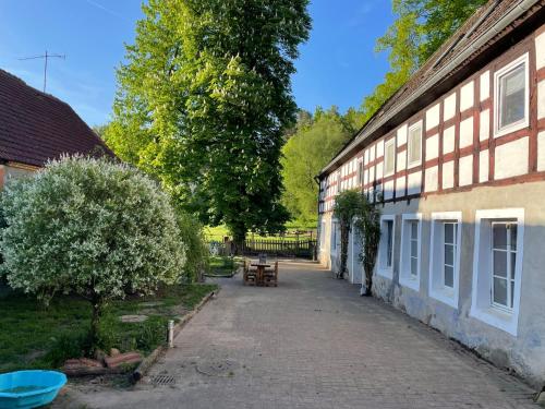 una persona è in piedi accanto a un edificio di Ferienzimmer Teiselsmühle Gehren Heideblick a Heideblick