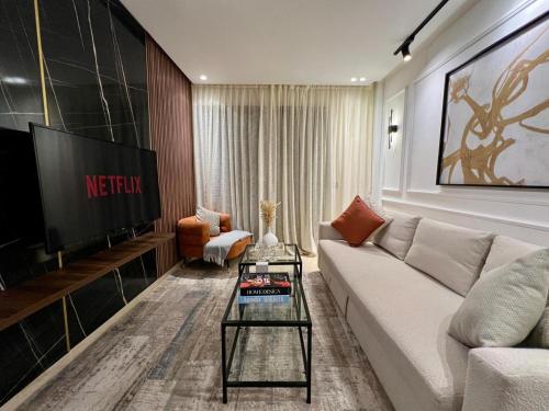 a living room with a white couch and a tv at Dynasty Estate, Appartements avec Terrasse et vue sur Twin Center in Maarif
