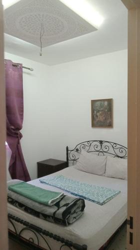 a bedroom with a bed with a green blanket on it at Appartement Familial Près d'aéroport Ibn Batouta Tanger in Tangier