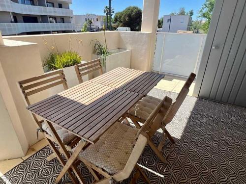 une table en bois et deux chaises assises sur un balcon dans l'établissement Appartement spacieux et lumineux dans une résidence à 650m de la mer, à Sérignan