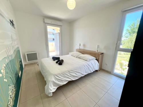 - une chambre dotée d'un lit blanc avec deux ours en peluche dans l'établissement Appartement spacieux et lumineux dans une résidence à 650m de la mer, à Sérignan