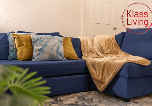 a blue couch with a blanket on it at Bute Apartment by Klass Living Coatbridge in Coatbridge