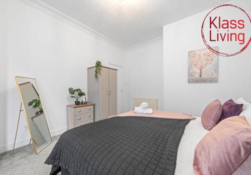 a bedroom with a bed with a black and pink blanket at Bute Apartment by Klass Living Coatbridge in Coatbridge