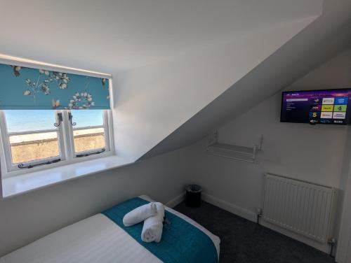 a bedroom with a bed and a window with a television at Acqua Beach Weymouth in Weymouth