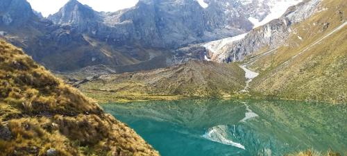 a mountain lake in the middle of a valley at HUAYHUASH TREK HOTSPRINGS start and finish in hotsprings 10 days one night purchase valued in 10 days trekking in Huaraz