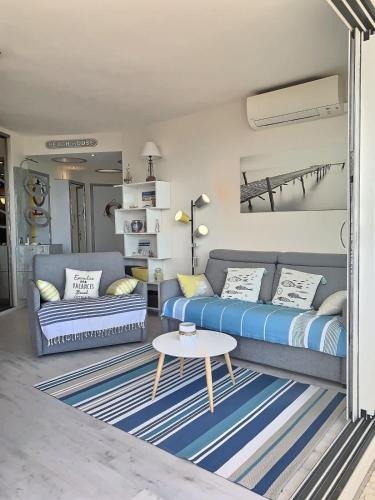 un salon avec un canapé bleu et une table dans l'établissement Magnifique appartement avec vue mer panoramique !, à Valras-Plage