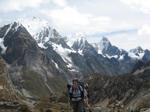 a man standing on the side of a mountain at HUAYHUASH TREK HOTSPRINGS start and finish in hotsprings 10 days one night purchase valued in 10 days trekking in Huaraz