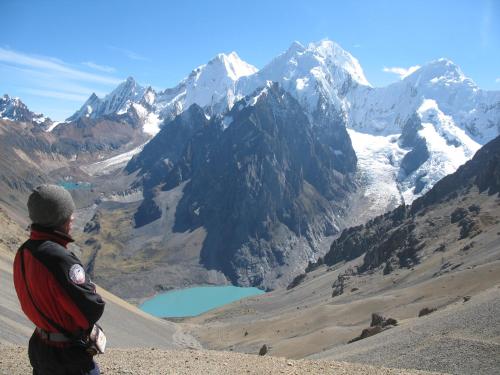 a man standing on top of a mountain looking at a lake at HUAYHUASH TREK HOTSPRINGS start and finish in hotsprings 10 days one night purchase valued in 10 days trekking in Huaraz