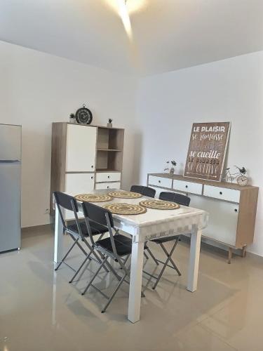 une cuisine avec une table, des chaises et un réfrigérateur dans l'établissement Agréable appartement pour 4 personnes à 150m de la plage, à Vias
