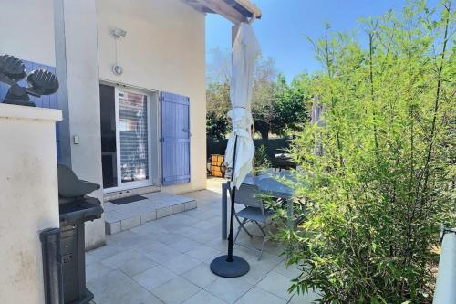 un patio avec une table et un parasol dans l'établissement Agréable pavillon avec grande terrasse pour 6 personnes, à Valras-Plage