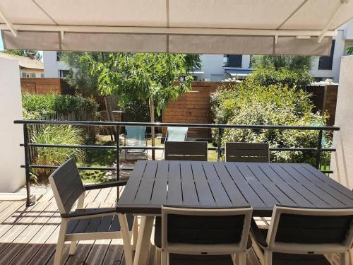 - une table de pique-nique et des chaises sur une terrasse avec un parasol dans l'établissement A 500m de la plage, pavillon confortable 6 personnes dans résidence recente, à Valras-Plage