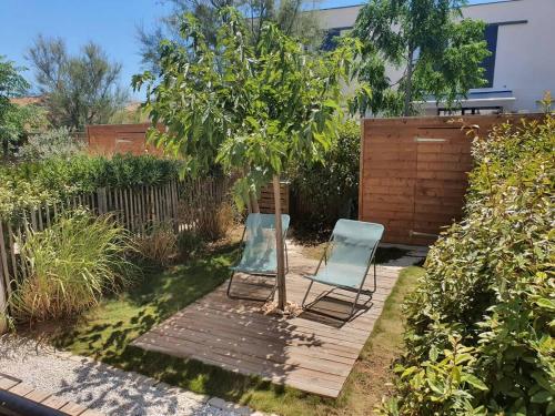 une chaise et un arbre sur une terrasse en bois dans l'établissement A 500m de la plage, pavillon confortable 6 personnes dans résidence recente, à Valras-Plage