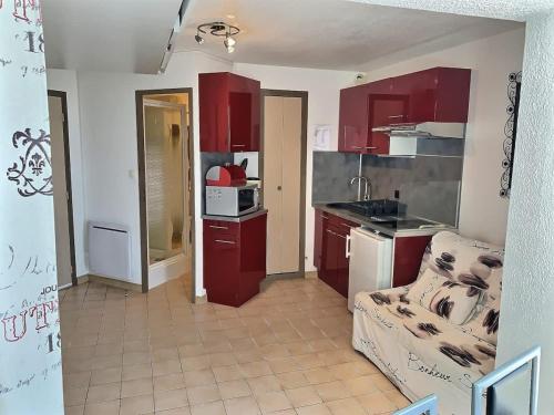 une petite cuisine avec des placards rouges et un four micro-ondes dans l'établissement Studio confortable avec vue mer et port, à Valras-Plage