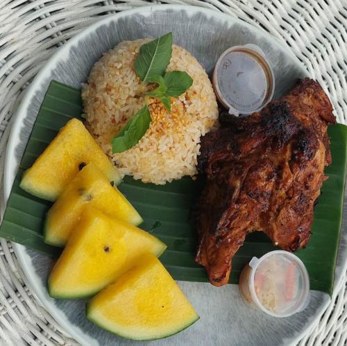 a plate of food with meat and rice and fruit at Family Studio - Pool, Kitchen & Netflix - Mountain & Pool Views - Nature Stay Near Underground River & Fireflies - With Onsite Restaurant & Free Billiards - Perfect Stop Between El Nido and Puerto City in Puerto Princesa