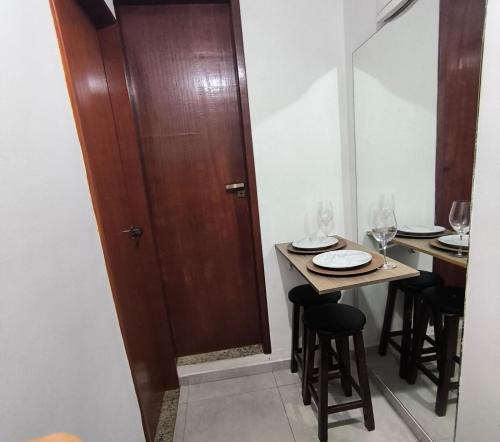 a dining room with a table and a wooden door at Vaccani Apart in Macaé