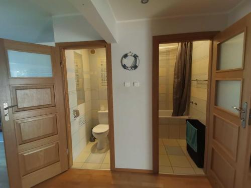e bagno con servizi igienici, doccia e porta. di Apartament na wakacje w Gdyni a Gdynia