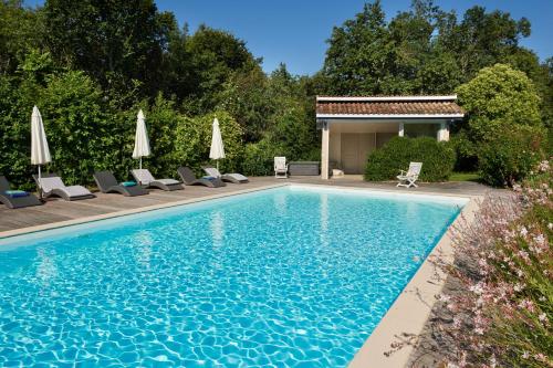 a swimming pool with chairs and umbrellas at Chambres d'Hôtes La Sauvageonne in Saint-Palais