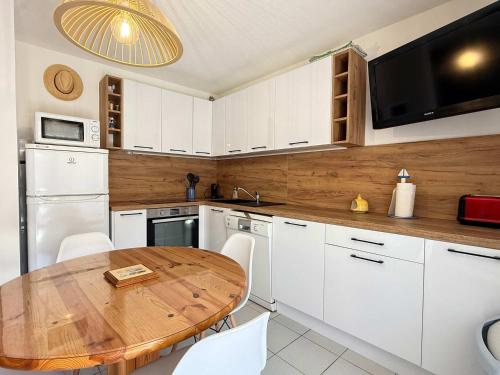 une cuisine avec une table en bois et des armoires blanches dans l'établissement LES JARDINS DE LA MER -Coquet pavillon à deux pas de la plage, à Valras-Plage