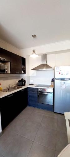 La cuisine est équipée de placards bleus et d'un réfrigérateur. dans l'établissement Appartement proche la mer dans une résidence calme, à Valras-Plage