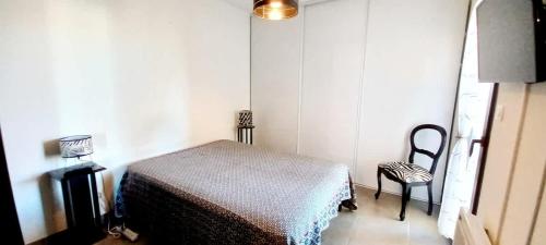 une petite chambre avec un lit et une chaise dans l'établissement Appartement proche la mer dans une résidence calme, à Valras-Plage