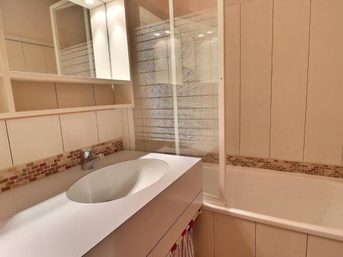 La salle de bains est pourvue d'un lavabo blanc et d'une baignoire. dans l'établissement Appartement 2* Méribel 4 pers, Balcon, Wi-Fi, Non-fumeur - FR-1-182-232, à Les Allues