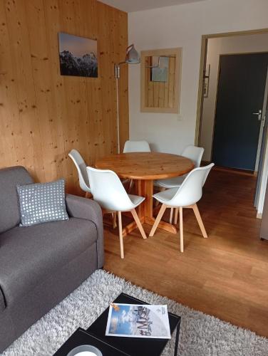 un salon avec une table en bois et des chaises blanches dans l'établissement Appartement les longes, à Saint-François-Longchamp