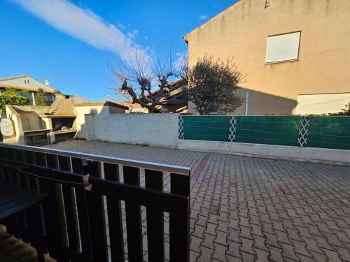 une clôture devant une maison avec un bâtiment dans l'établissement Valras-Loc - Studio avec terrasse et exterieur, à Valras-Plage