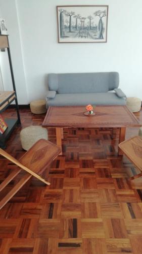 a living room with a wooden table and a blue couch at Marciloui in Antsirabe