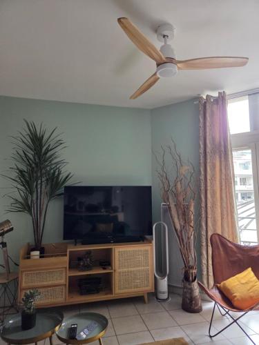 a living room with a flat screen tv and a ceiling fan at L'Appart Aixois - au coeur de la ville - Location in Aix-les-Bains