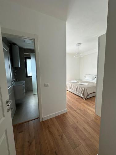 a white bedroom with a bed and a wooden floor at Aurela Apartment in Lezhë