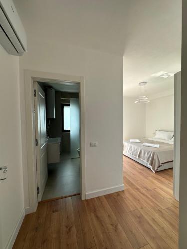 a white bedroom with a bed and a wooden floor at Aurela Apartment in Lezhë