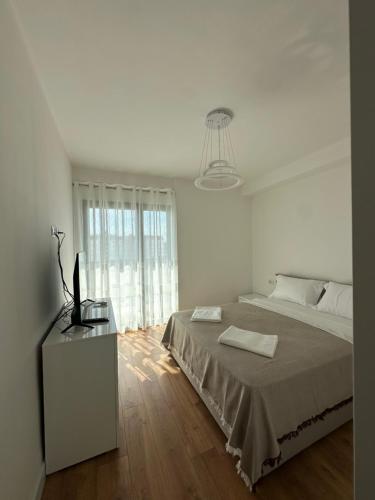 a white bedroom with a large bed and a television at Aurela Apartment in Lezhë