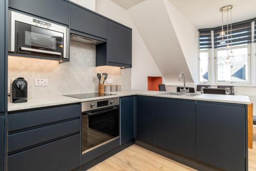 a kitchen with blue cabinets and a sink at Remodelled Luxury 3 Bed Apartment in Aberdeen