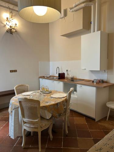 a kitchen with a table and chairs and a kitchen with white cabinets at Le Suite Di Faenza in Faenza