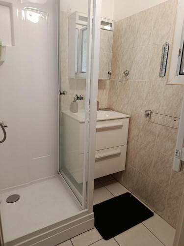 une salle de bain blanche avec une douche et un lavabo dans l'établissement Appartement Marseillan-Plage, à Marseillan