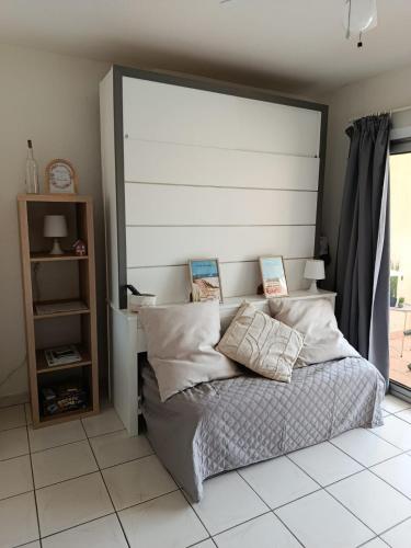 - un lit avec une grande tête de lit dans une chambre dans l'établissement Appartement Marseillan-Plage, à Marseillan