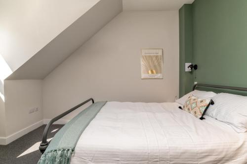 a bedroom with a white bed with a green wall at Remodelled Luxury 3 Bed Apartment in Aberdeen