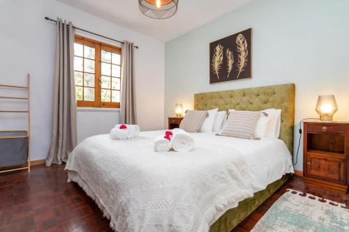 une chambre avec un grand lit avec deux serviettes dessus dans l'établissement The Chestnut Garden - Farm House, à Fenais da Luz