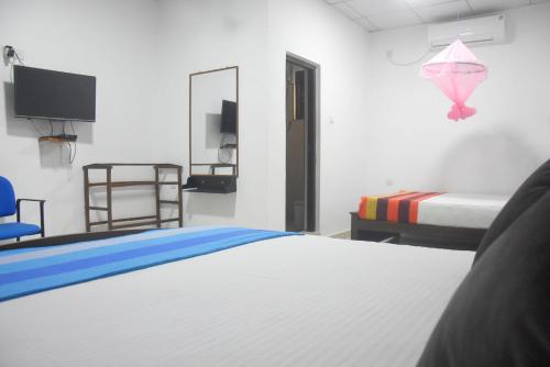 a bedroom with two beds and a tv and a bed at CFC Holiday Home in Anuradhapura