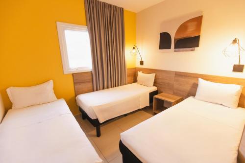two beds in a room with yellow walls at Hotel Euro Suite São Jose do Rio Preto by Nacional Inn in Sao Jose do Rio Preto