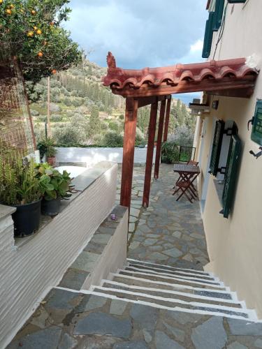 a wooden pergola on a building with a stone walkway at Κυκλαδίτικο σπίτι in Andros