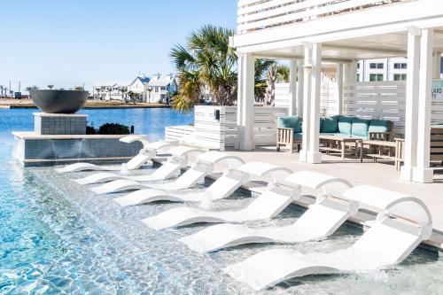 a group of white lounge chairs in a pool at Fridays Comin 132 BAR in Mustang Beach