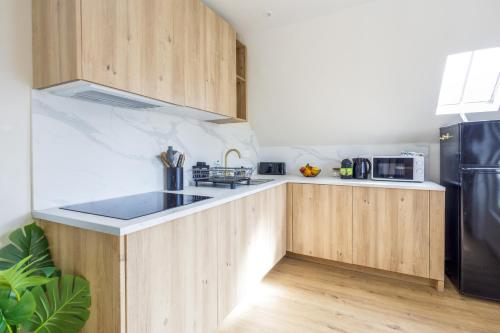 une cuisine avec des armoires en bois et un réfrigérateur en acier inoxydable dans l'établissement Duplex design à 3min plage 2 SDB & 3 couchages, à Villers-sur-Mer