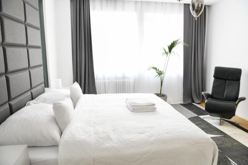 a bedroom with a white bed and a black chair at Alexander library apartment in Košice