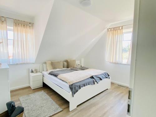 a white bedroom with a white bed and windows at Haus Lieblingsquartier in Tating