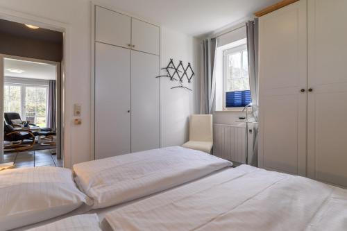 une chambre avec un grand lit blanc et une chaise dans l'établissement Auszeit unter Reet, à Böhl