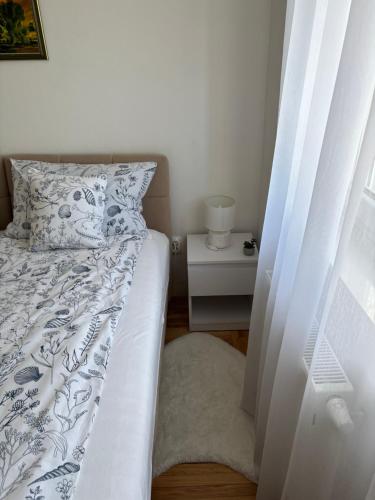 a bedroom with a bed with a white bedspread and a side table at Apartman M&M Osijek in Osijek