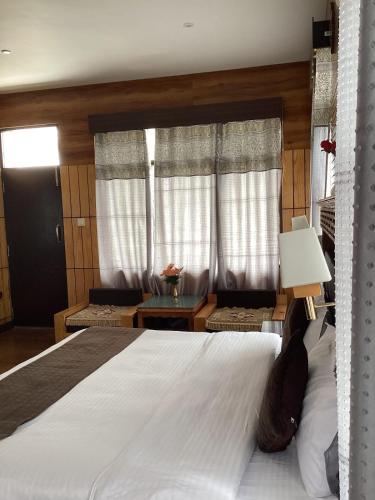a bedroom with a large white bed and a window at Hotel Blue Pine in Kyelang